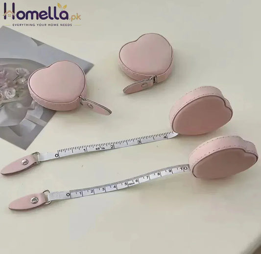 Pink heart-shaped measuring tape with a case on a light surface