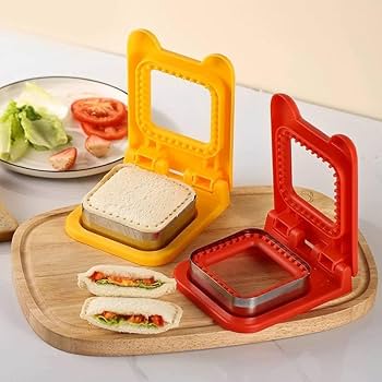 Yellow and red sandwich maker on a wooden board with ingredients.