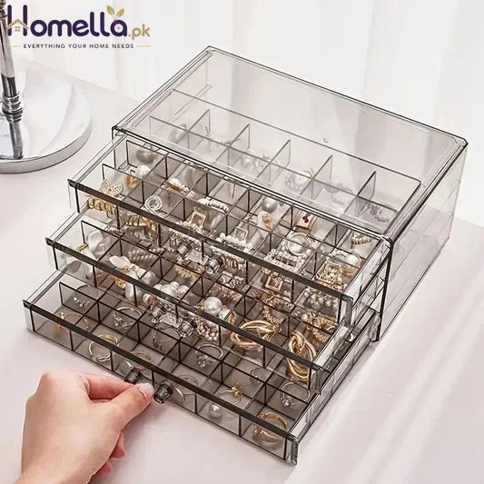 Clear jewelry organizer with multiple compartments filled with earrings on a white surface.