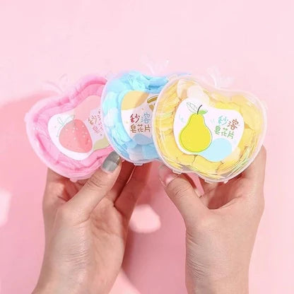 Three small containers with colorful designs held by hands against a pink background