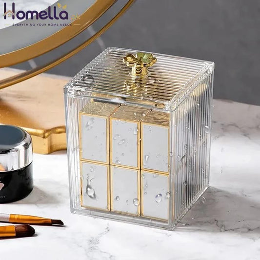 Clear decorative box with gold accents on a marble surface with makeup items.