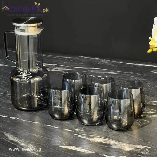 Set of smoked glass tumblers and a carafe on a marble surface with a dark background.