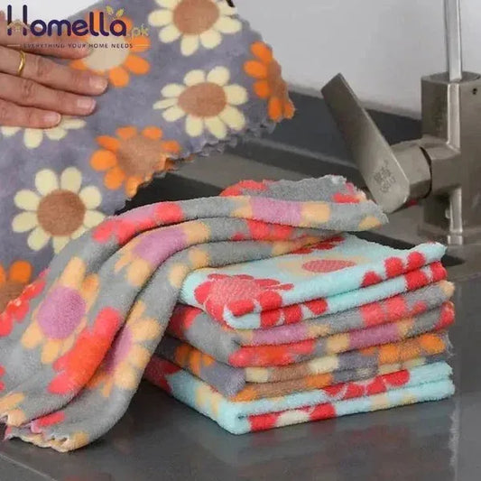 Stack of colorful patterned towels on a kitchen counter with a hand holding a towel.