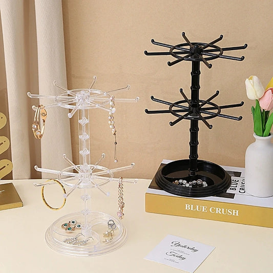 Two jewelry display stands on a table with books and a vase in the background.