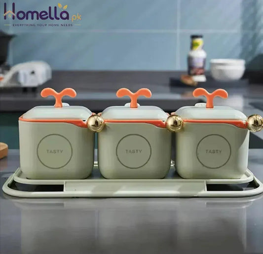 Three green containers with orange lids on a kitchen counter