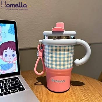 Pink and checkered insulated mug with handle on a wooden desk next to a laptop.