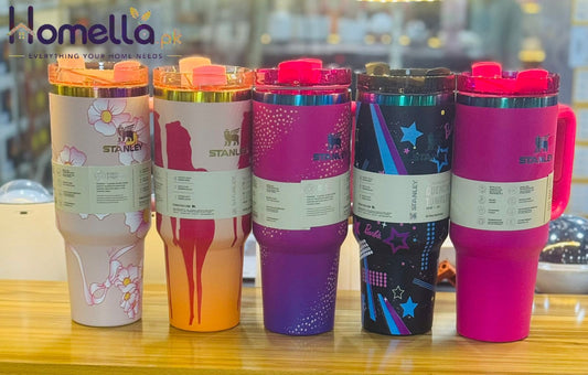 Five colorful tumblers with different designs on a wooden surface.