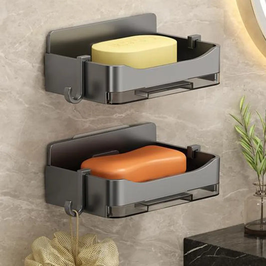 Two gray wall-mounted soap holders with yellow and orange soaps on a tiled wall.