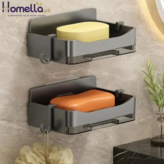 Two gray wall-mounted soap holders with yellow and orange soaps on a tiled wall.