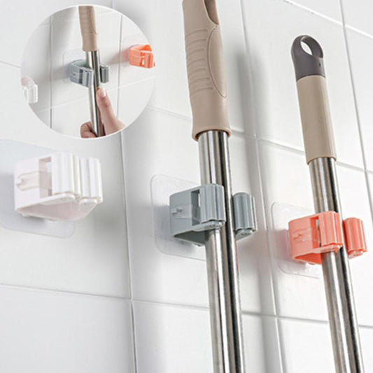 Mop and broom holders on a tiled wall with close-up of hand using holder.