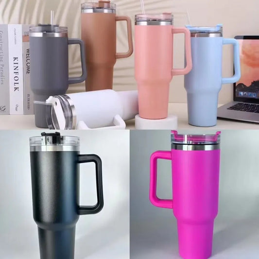 Collection of colorful insulated travel mugs on a desk with books and a laptop.