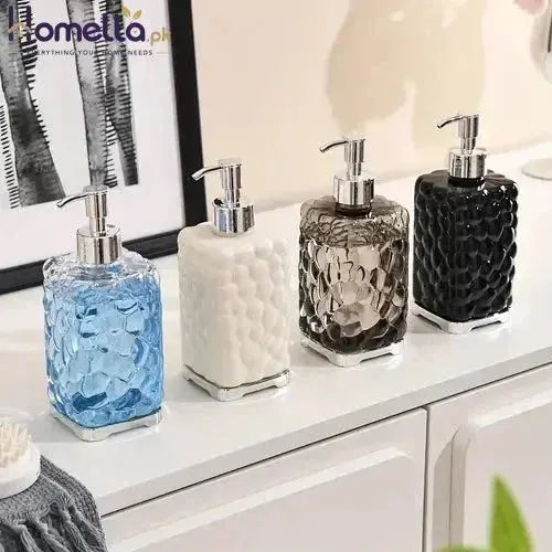 Set of four decorative soap dispensers on a bathroom counter.