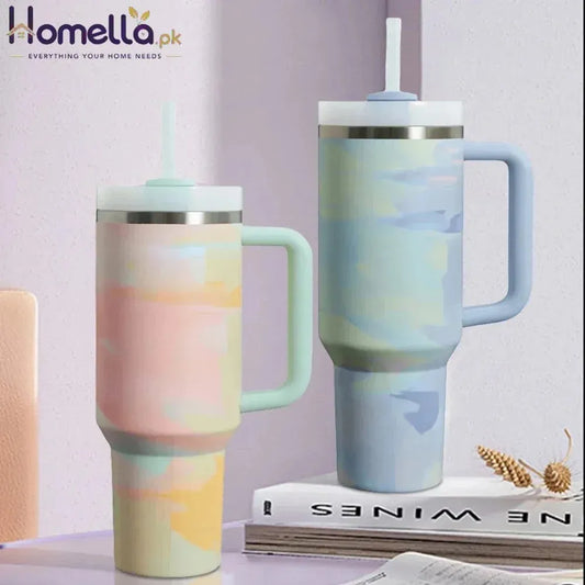 Two marbled pattern tumblers on a surface with a book and decorative items in the background.