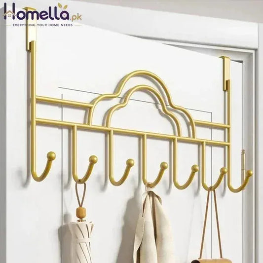 Gold over-the-door hook rack with clothes on a white door