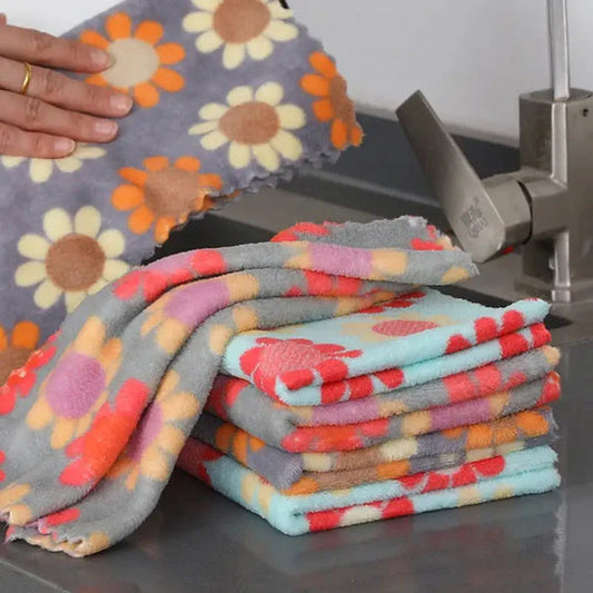 Stack of colorful patterned towels on a kitchen counter with a hand holding a towel.