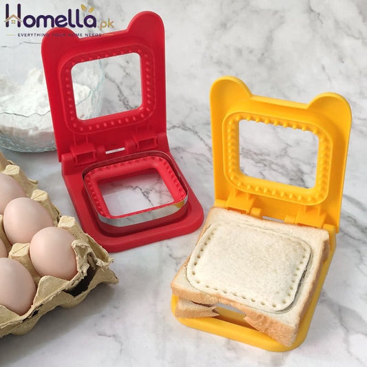 Two sandwich makers, one red and one yellow, on a marble surface with eggs and bread.