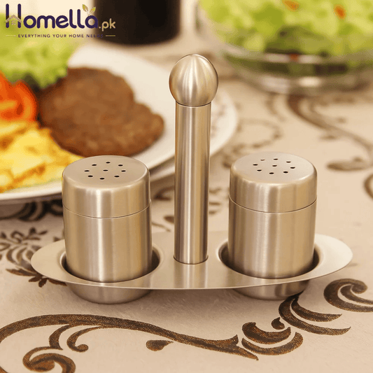 Stainless steel condiment set on a decorative tablecloth with food in the background